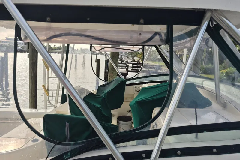 Slide: The Image of 1996 Pursuit 3000 Offshore boat interior with green covers, docked by the water. - 13