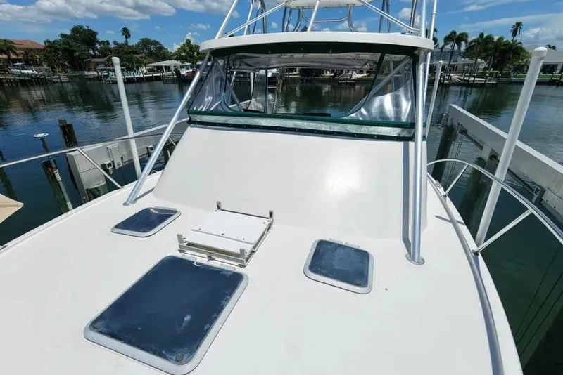 Slide: The Image of 1996 Pursuit 3000 Offshore boat docked by a serene waterfront under a clear blue sky. - 2