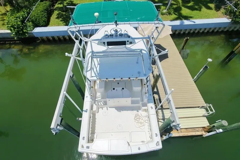 Slide: The Image of 1996 Pursuit 3000 Offshore boat docked, aerial view, green canopy, wooden pier, calm water. - 6