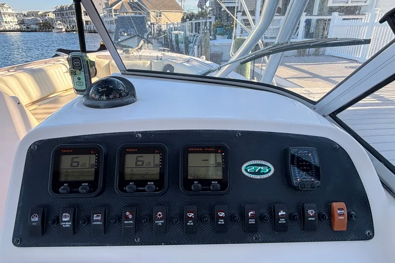 Slide: The Image of Grady-White Freedom 275 boat dashboard with gauges and controls, docked by waterfront homes. - 11