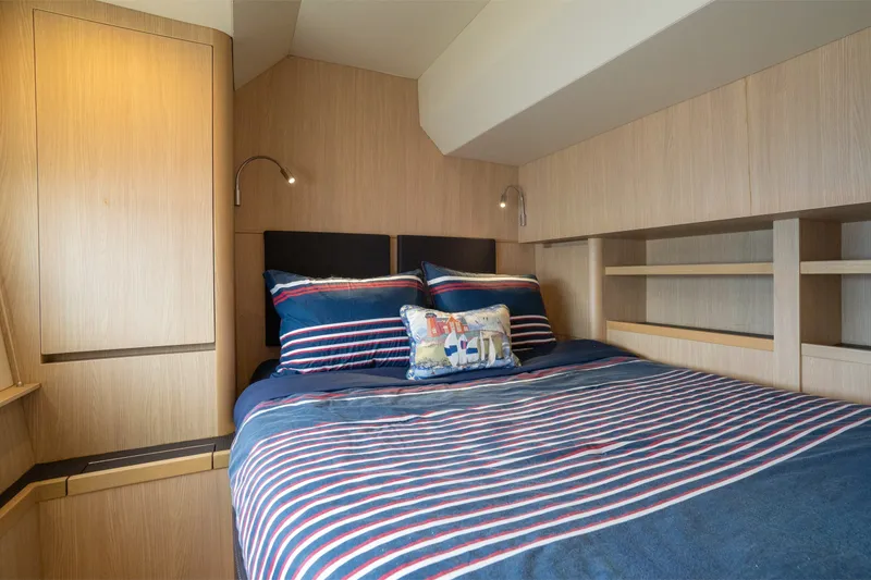 Slide: The Image of Cozy bedroom interior on 2018 Aquila 44 Yacht with striped bedding and wooden shelves. - 30