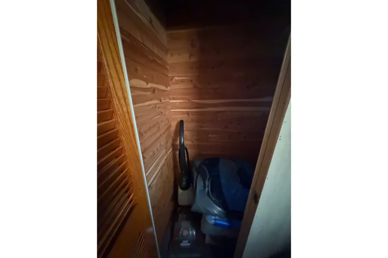 Slide: The Image of Small wooden storage space with vacuum cleaner and miscellaneous items. - 18