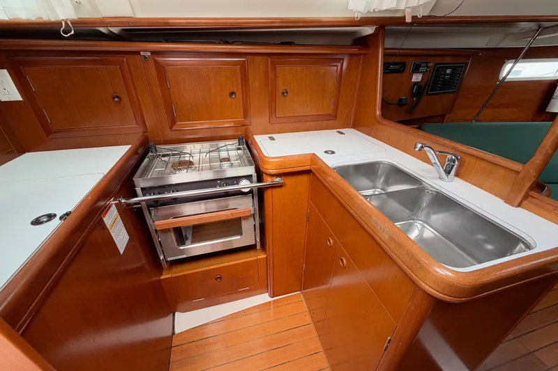 Slide: The Image of Galley of 2001 Beneteau Oceanis 331 sailboat with stove, sink, and wooden cabinetry. - 5