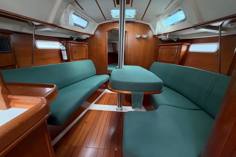 Slide: The Image of Interior of 2001 Beneteau Oceanis 331 sailboat with green seating and wooden finishes. - 2