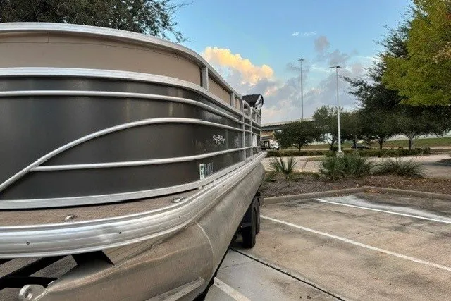 Slide: The Image of 2021 Sun Tracker Party Barge 24 DLX pontoon boat parked outdoors, showcasing sleek design. - 16