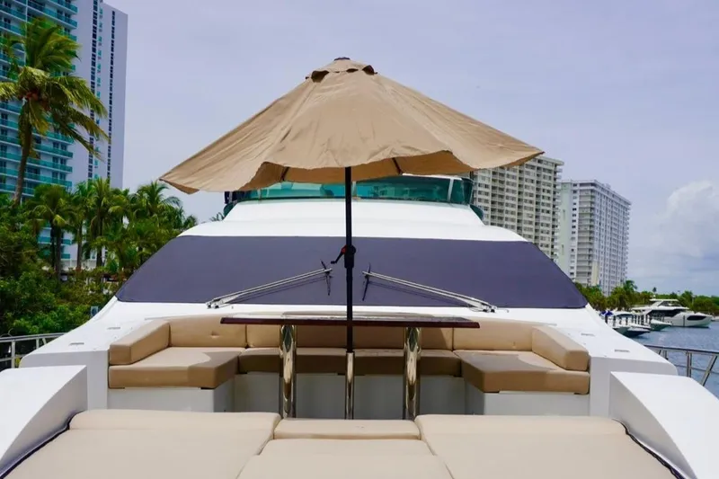 Slide: The Image of Luxurious 2015 Azimut 84 yacht deck with seating and umbrella, docked near palm trees and buildings. - 24