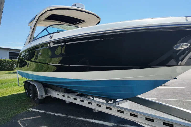 The Image of 2024 Sea Ray SLX 310 boat on trailer, sleek black and blue design. - 0
