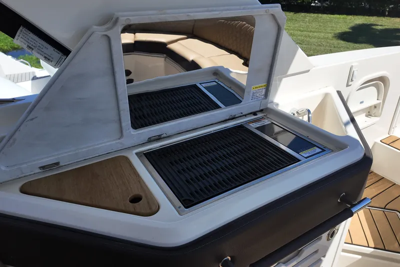 Slide: The Image of 2024 Sea Ray SLX 310 boat grill station with open lid and seating area. - 14