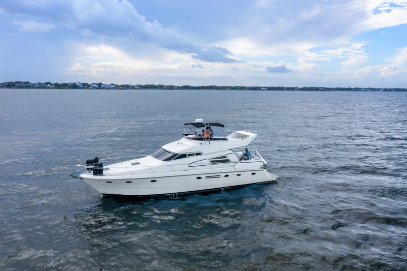 Slide: The Image of 1993 Johnson 56 Motor Yacht cruising on open water under a cloudy sky. - 47