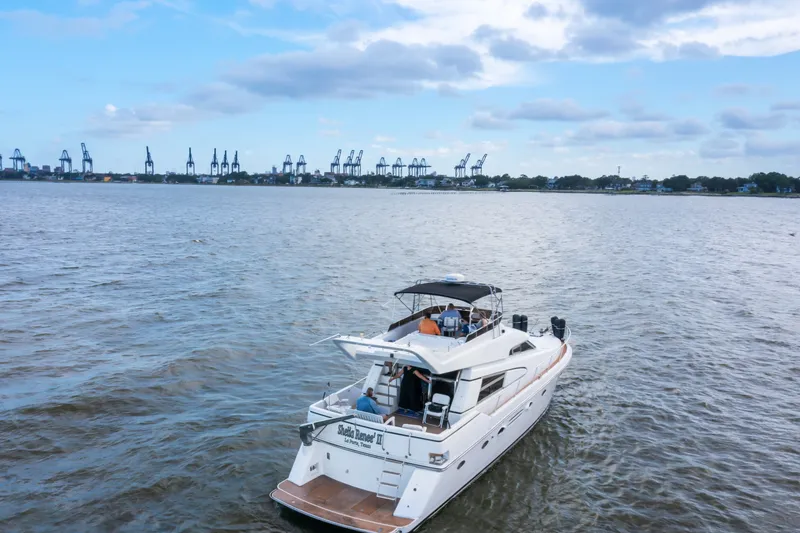Slide: The Image of 1993 Johnson 56 Motor Yacht cruising on a calm river with cranes in the background. - 50