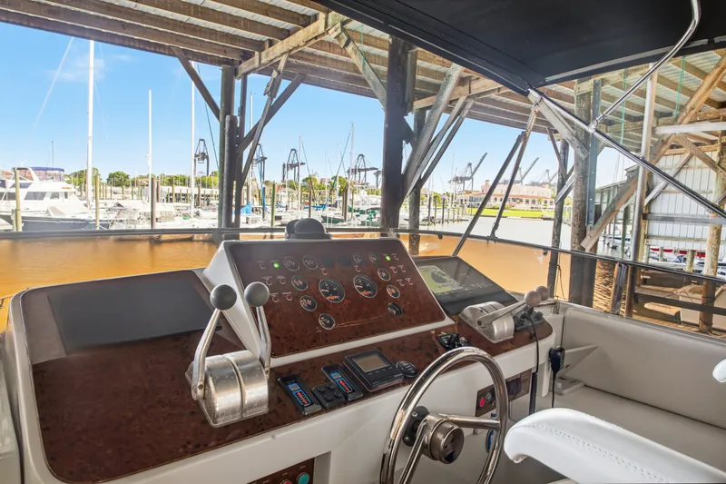 Slide: The Image of Helm of 1993 Johnson 56 Motor Yacht in marina setting, showcasing controls and gauges. - 26