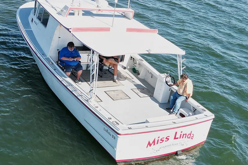 Slide: The Image of ```json { "alt_text": "2002 Donelle Express Down East Lobster Boat 'Miss Linda' on water with three people onboard." } ``` - 35