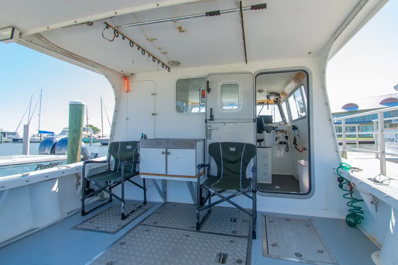 Slide: The Image of 2002 Donelle Express Down East Lobster Boat interior with chairs and dock view. - 24