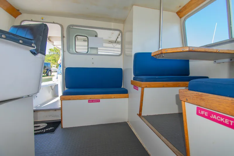 Slide: The Image of Interior of 2002 Donelle Express Down East Lobster Boat with blue seating and life jacket storage. - 5