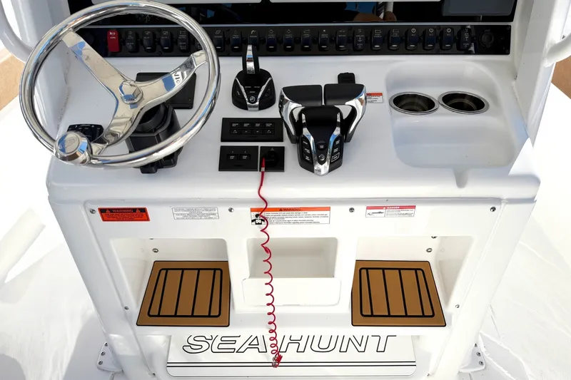Slide: The Image of 2025 Sea Hunt Gamefish 30FS helm with steering wheel, controls, and cup holders. - 23