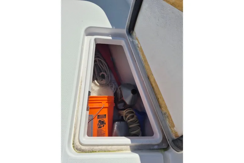 Slide: The Image of Storage compartment on a 2000 Pro-Line 24 Sport boat with ropes and an orange bucket. - 31