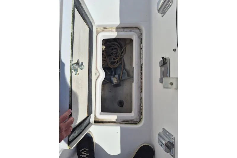 Slide: The Image of Open storage compartment on a 2000 Pro-Line 24 Sport boat, revealing anchor and rope. - 43