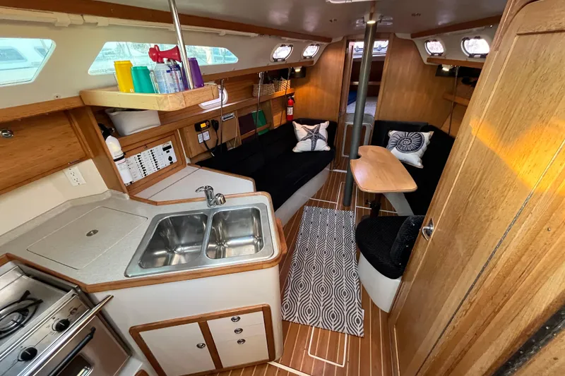 Slide: The Image of Interior of 2005 Catalina 320 sailboat with kitchen, seating, and wooden finishes. - 1