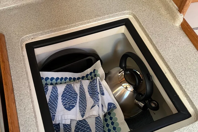 Slide: The Image of Storage compartment in a 2005 Catalina 320 with kettle and fish-patterned towels. - 11