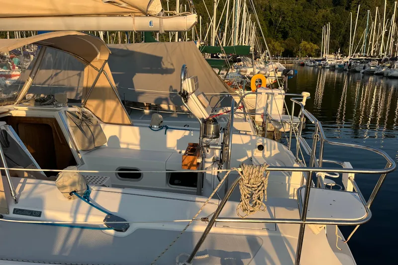 Slide: The Image of 2005 Catalina 320 sailboat docked in a marina, surrounded by other boats. - 25