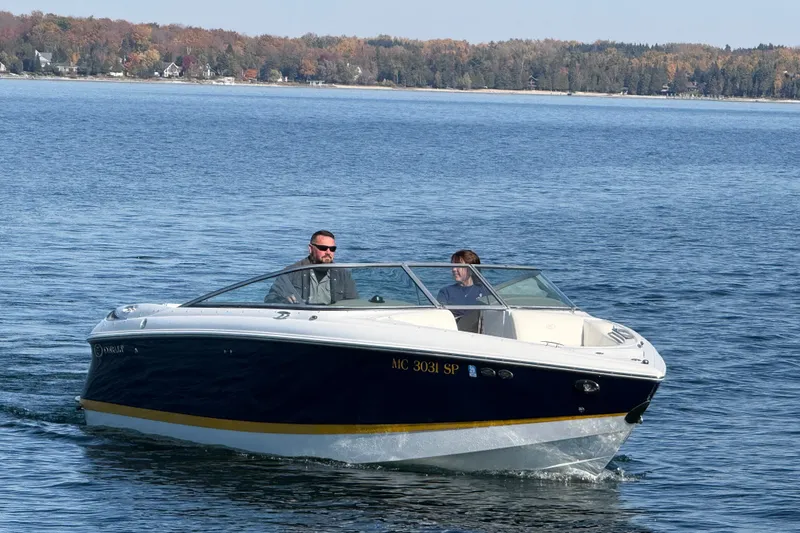 Slide: The Image of 2004 Cobalt 250 boat cruising on a lake with autumn trees in the background. - 1