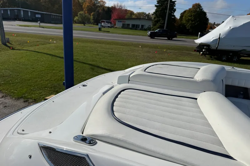 Slide: The Image of 2004 Cobalt 250 boat with white cushioned seating, parked near a road. - 12