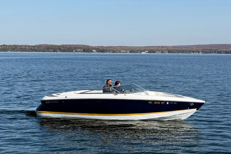 The Image of 2004 Cobalt 250 boat cruising on a calm lake under clear skies. - 2