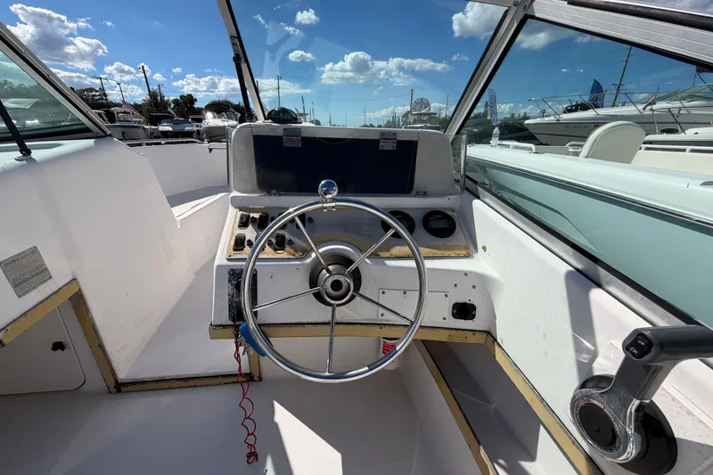 Slide: The Image of 1994 Grady-White Tournament 197 boat cockpit with steering wheel and control panel under blue sky. - 13