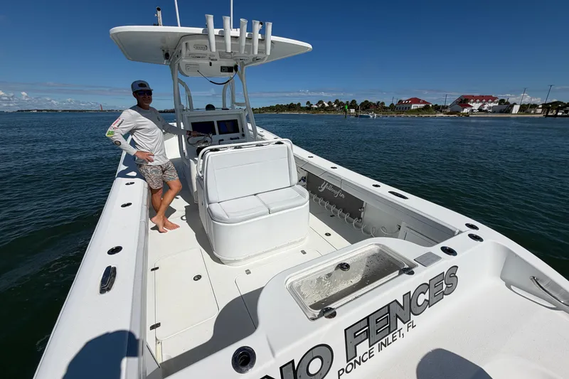 Slide: The Image of 2010 Yellowfin 32 Offshore boat on water, person standing, sunny day, coastal background. - 31