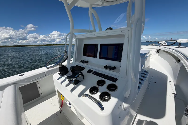Slide: The Image of 2010 Yellowfin 32 Offshore boat cockpit with dual screens, steering wheel, and ocean view. - 37