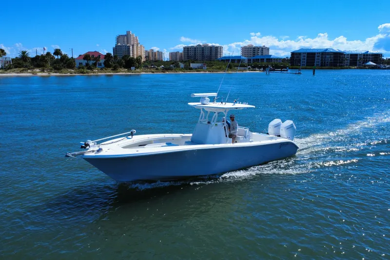Slide: The Image of 2010 Yellowfin 32 Offshore boat cruising on a sunny day near coastal buildings. - 10