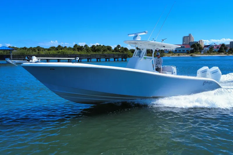 Slide: The Image of 2010 Yellowfin 32 Offshore boat cruising on a sunny day near a coastal area. - 12