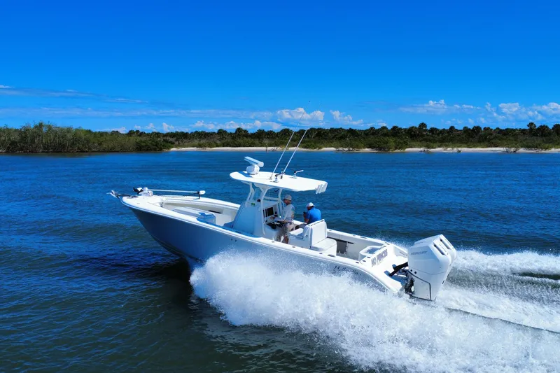 Slide: The Image of 2010 Yellowfin 32 Offshore boat cruising on blue water near a lush shoreline. - 6