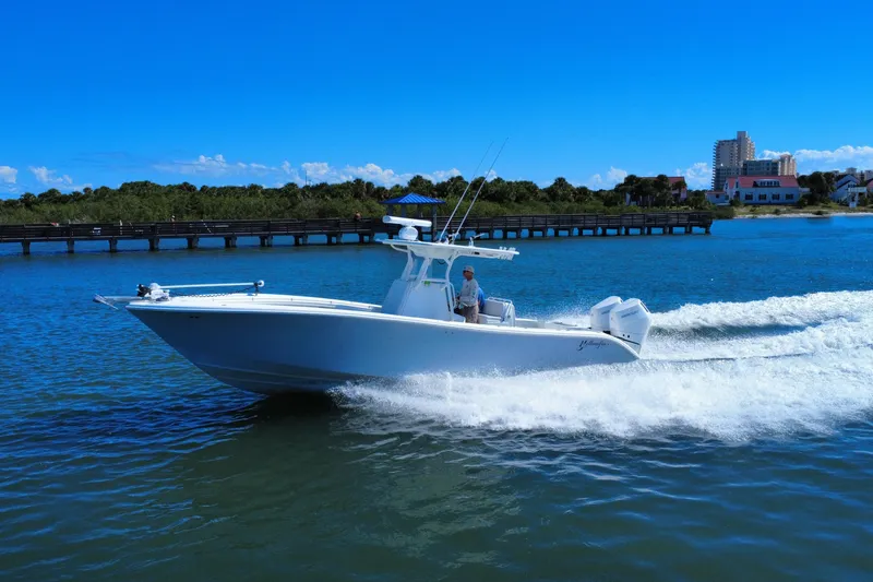 Slide: The Image of 2010 Yellowfin 32 Offshore boat cruising on a sunny day near a coastal pier. - 7