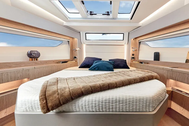 Slide: The Image of Das Bild zeigt eine luxuriöse Kabine mit einem großen Bett, Holzakzenten und Oberlichtern. - 42