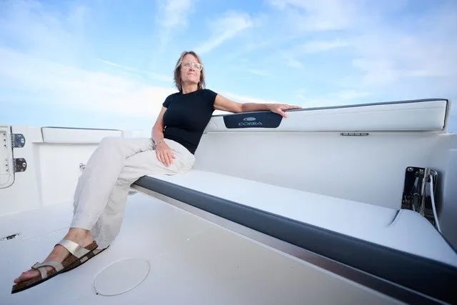 Slide: The Image of A woman sits relaxed on a bench in the Cobia 250 DC boat. - 19