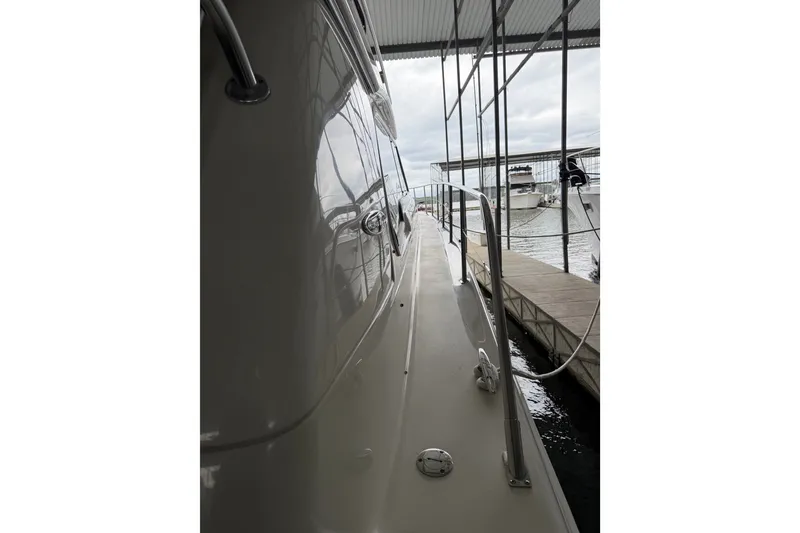 Slide: The Image of 2003 Sea Ray 480 Sedan Bridge yacht docked, showcasing sleek side view and railing. - 2