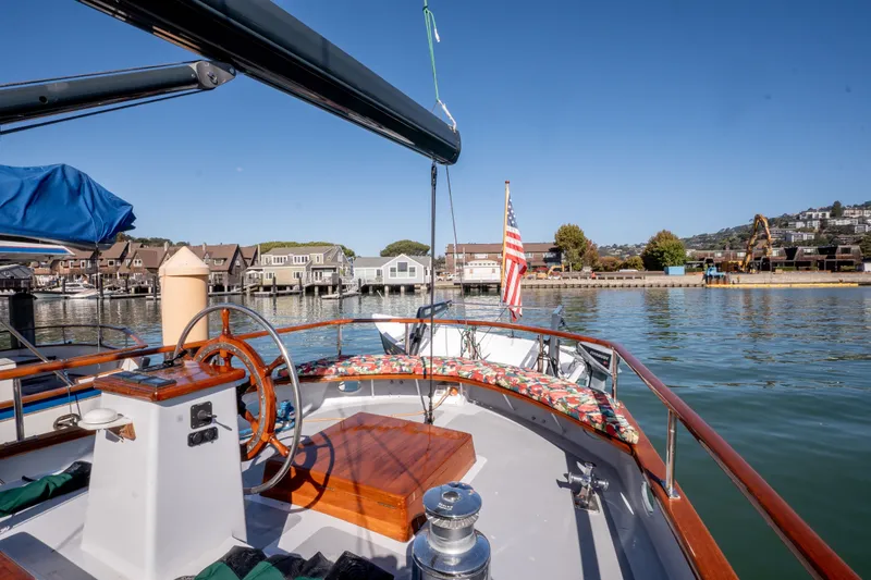 Slide: The Image of 1981 Thackwray Motorsailor yacht with scenic harbor view, featuring wooden helm and American flag. - 14