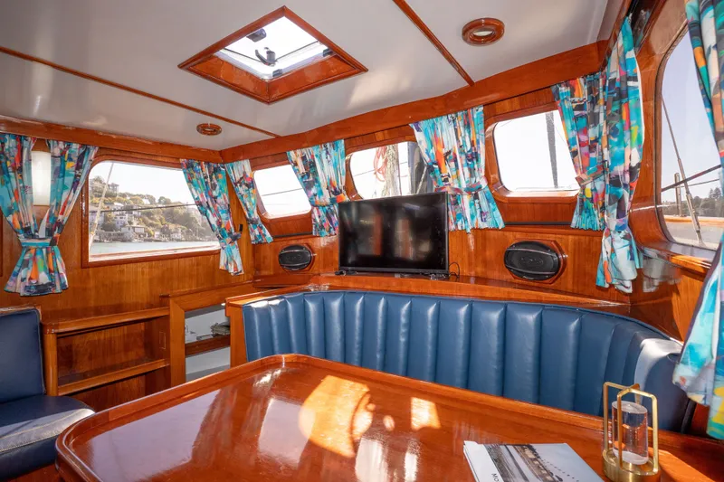 Slide: The Image of Interior of 1981 Thackwray Motorsailor with wood paneling, blue seating, and colorful curtains. - 120