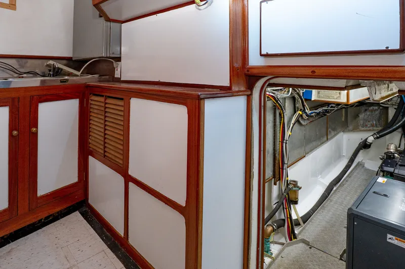 Slide: The Image of Engine room of a 1981 Thackwray Motorsailor with wooden cabinetry and visible wiring. - 90