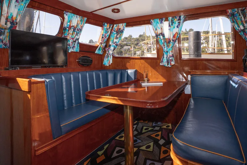 Slide: The Image of Interior of 1981 Thackwray Motorsailor with blue seating, wooden table, and colorful curtains. - 124