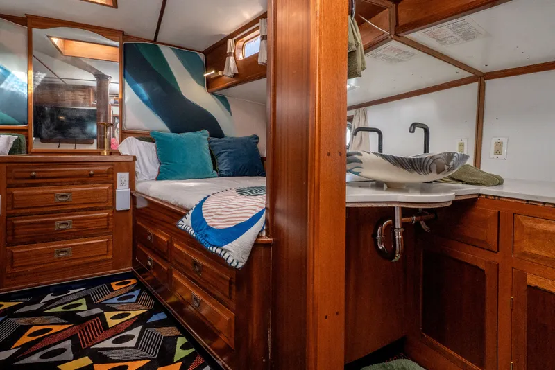 Slide: The Image of Interior of 1981 Thackwray Motorsailor with wooden cabinetry, colorful decor, and cozy bedding. - 103