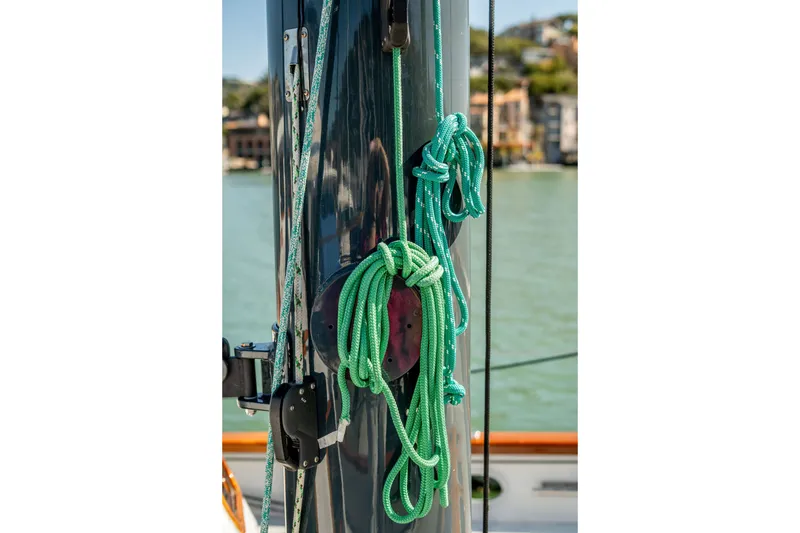 Slide: The Image of Close-up of ropes on a 1981 Thackwray Motorsailor mast, with a scenic waterfront background. - 46