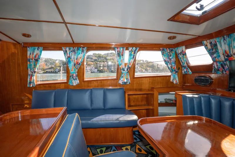 Slide: The Image of Interior of 1981 Thackwray Motorsailor with blue seating, colorful curtains, and wooden finishes. - 121