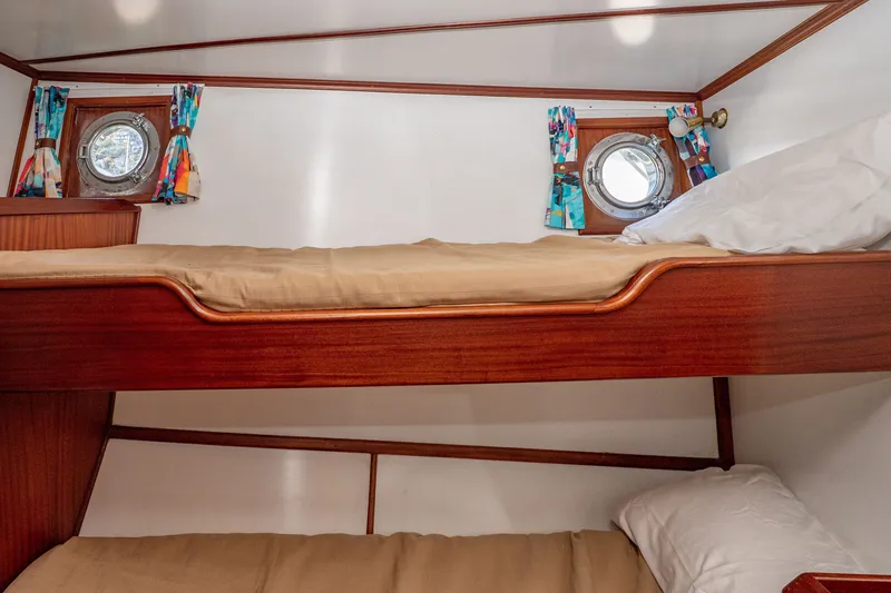 Slide: The Image of Interior of 1981 Thackwray Motorsailor with wooden bunk beds and colorful porthole curtains. - 82
