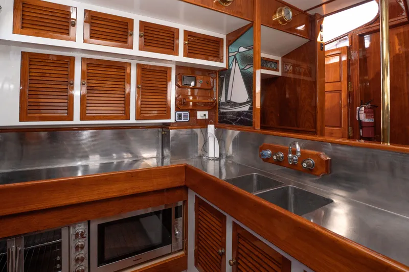 Slide: The Image of 1981 Thackwray Motorsailor kitchen with wooden cabinets, stainless steel counters, and dual sinks. - 95