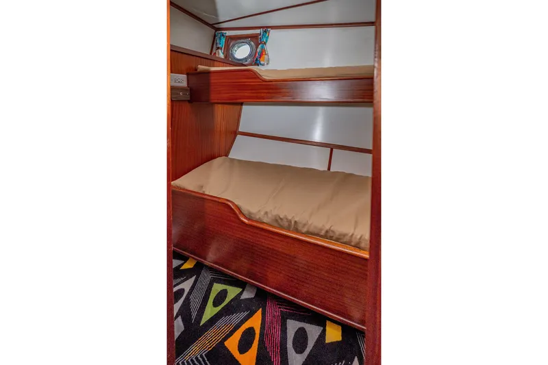 Slide: The Image of Bunk beds in 1981 Thackwray Motorsailor cabin with colorful carpet and porthole window. - 81