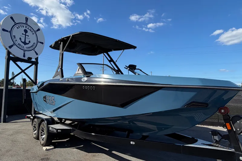 The Image of 2023 Axis T220 boat on trailer at dealership under clear blue sky. - 0