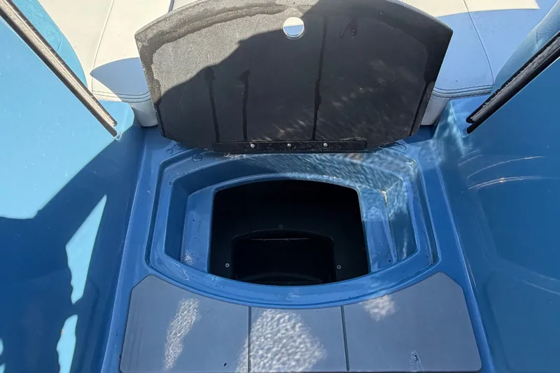 Slide: The Image of An open storage compartment on a blue boat with gray upholstery. - 44