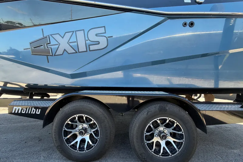 Slide: The Image of 2023 Axis T220 boat on trailer with stylish wheels and Malibu branding. - 82